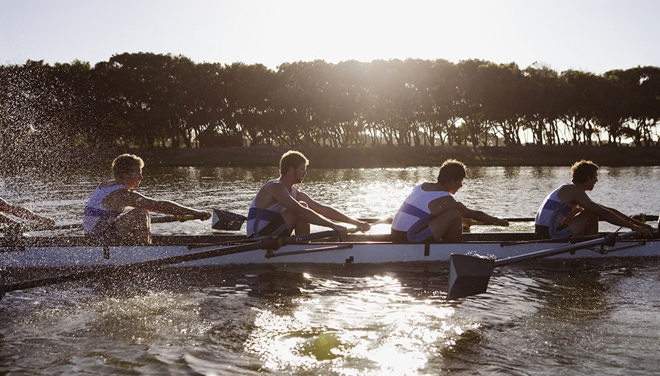 Team of well-coordinated rowers paddling a boat. 